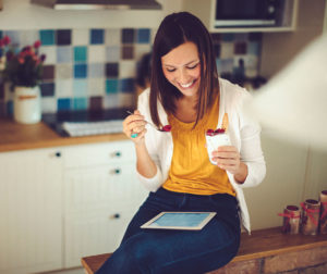 woman eating raspberries while doing an online program