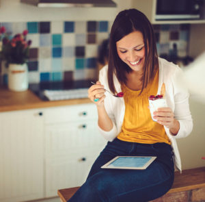 woman eating raspberries while doing an online program