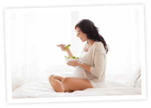 Pregnant woman eating on bed